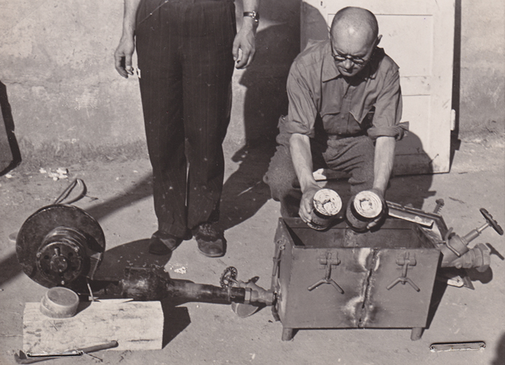 Der Lieutenant der US Army und ehemalige KZ-Häftling Jack Taylor mit der Gaseinfüllvorrichtung der Gaskammer und Zyklon B-Dosen kurz nach der Befreiung im Mai 1945 (US National Archives and Records Administration)